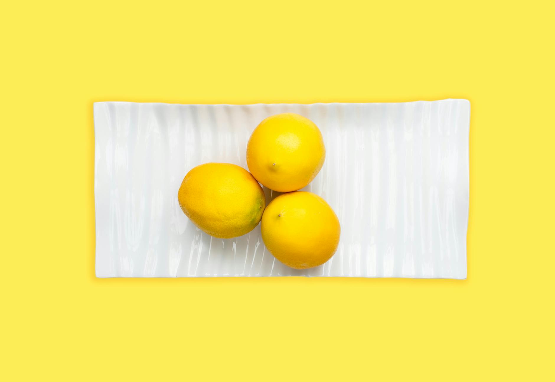 Fresh lemons arranged on a white plate against a bright yellow background, symbolizing restored sensitivity and renewed pleasure