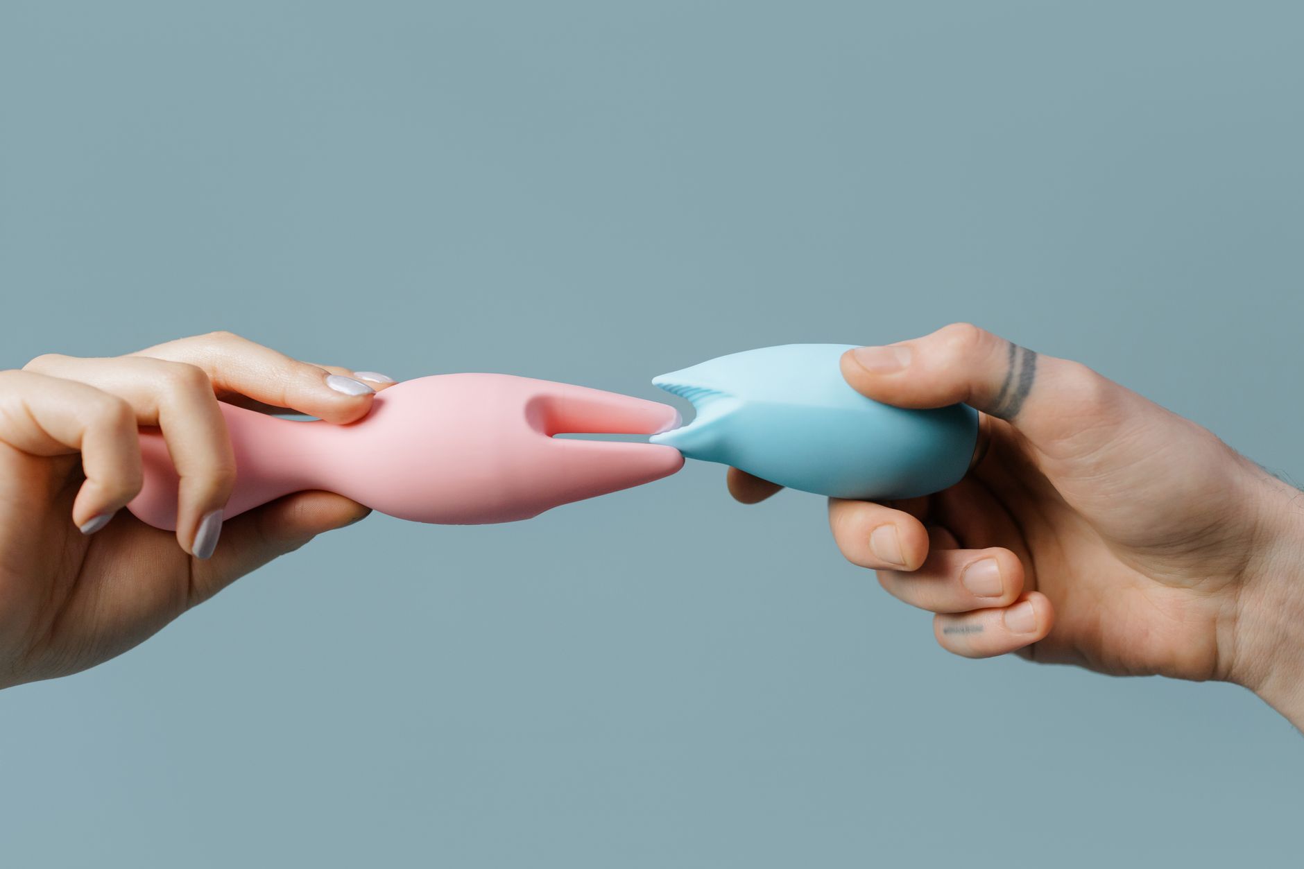 Hands holding a blue personal massager against a cozy knitted sweater