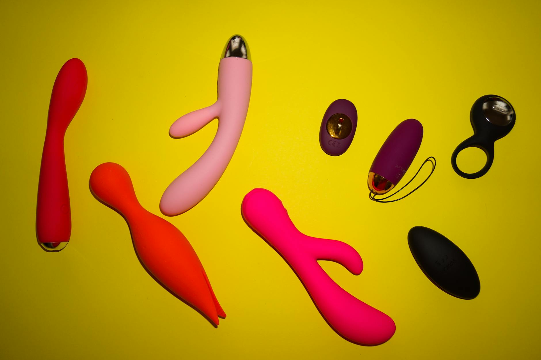 Colorful clitoral vibrators displayed on a bright yellow surface